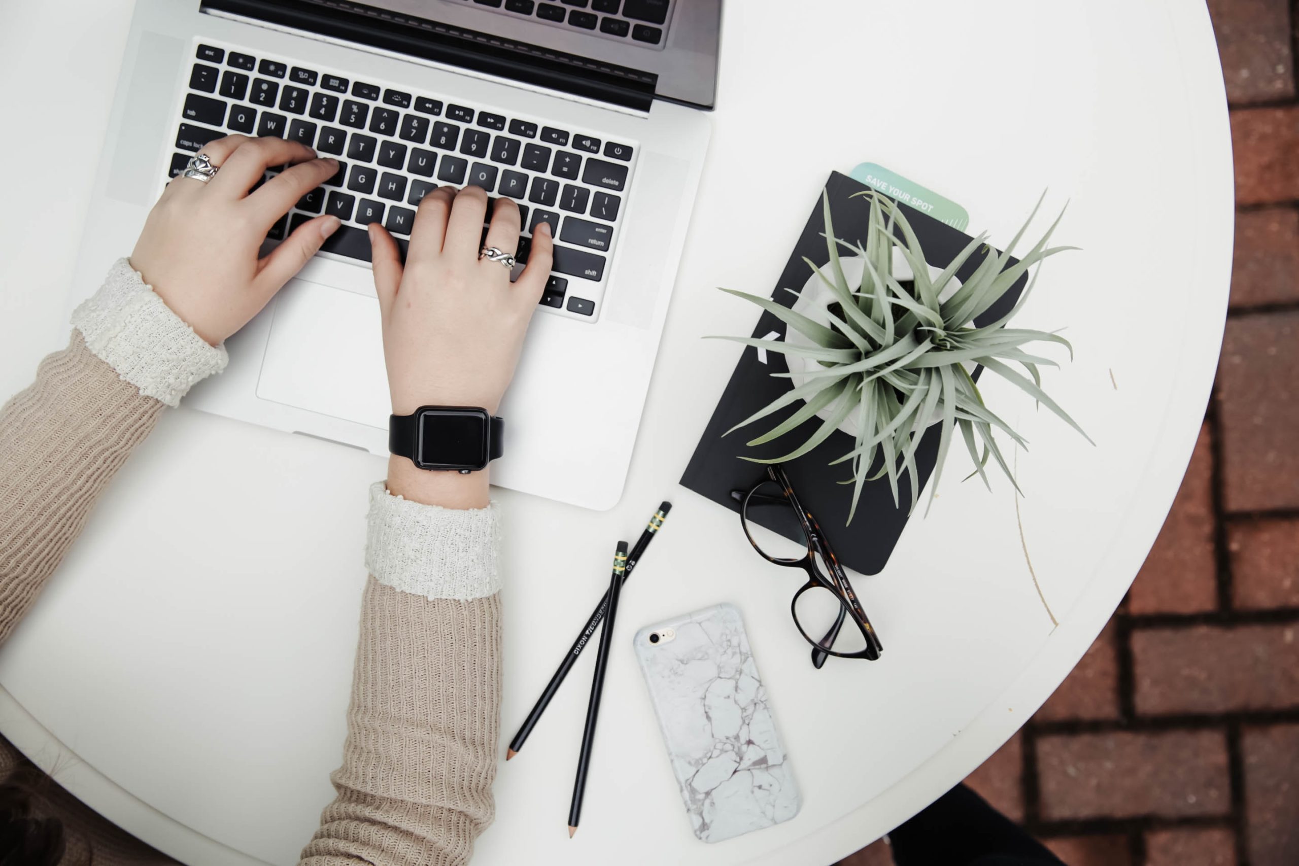 woman typing on computer at desk with office plant.