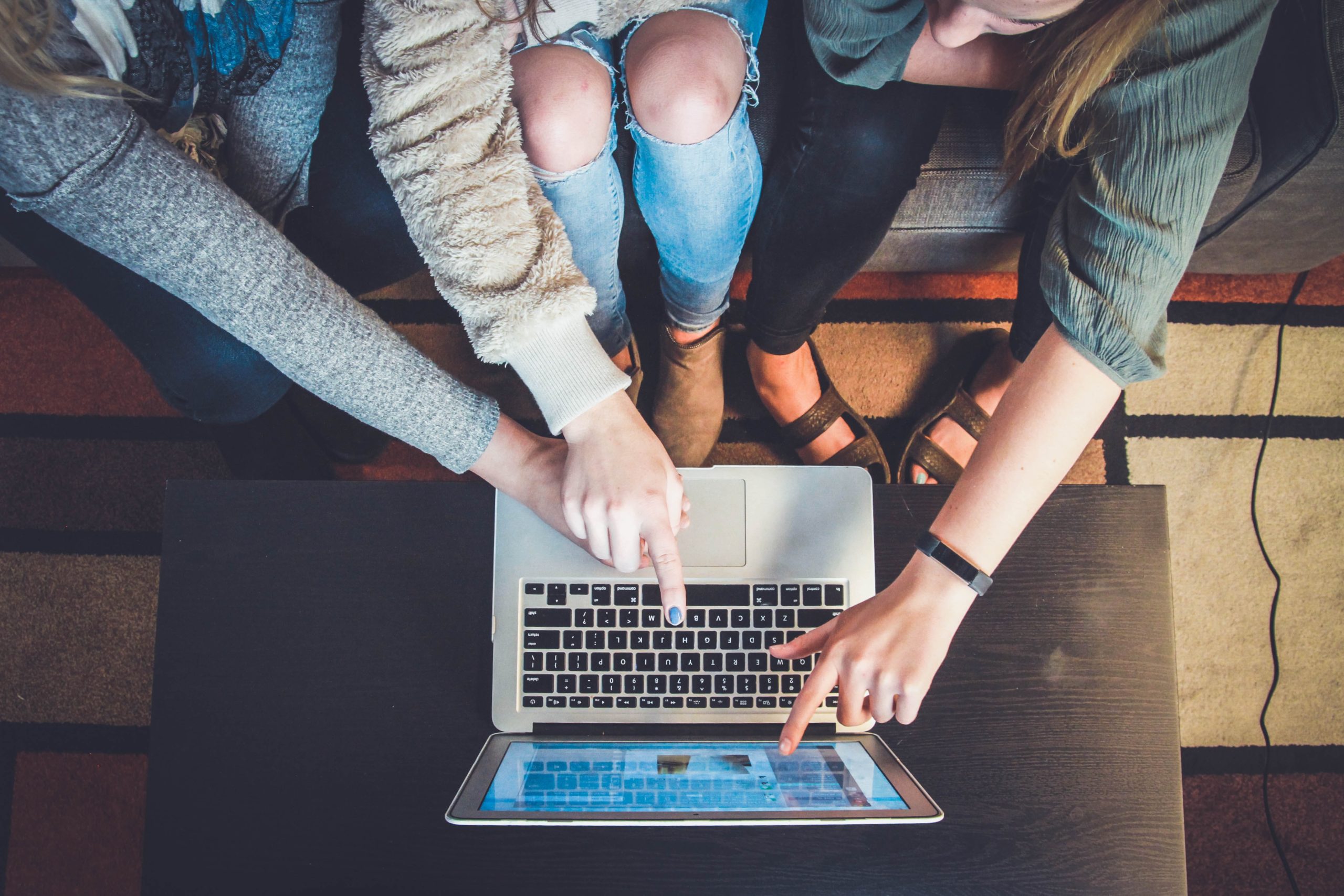 photo of 3 women in front of a laptop pointing at the screen